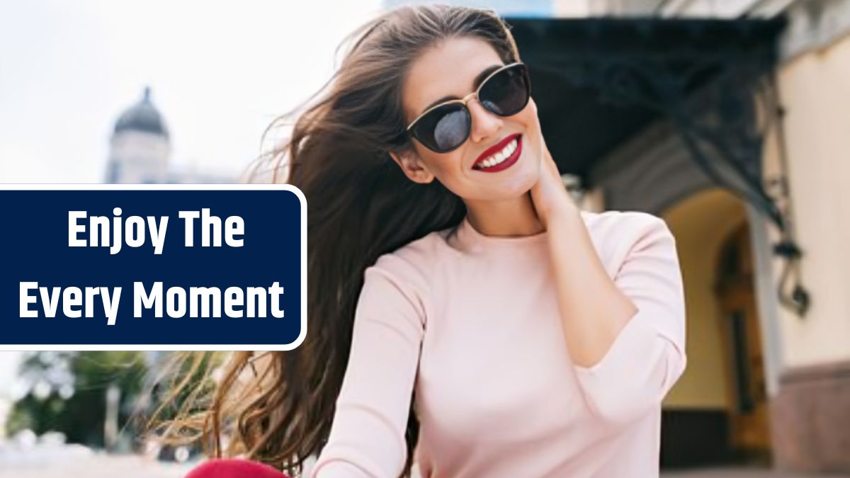 Closeup portrait of attractive girl in sunglasses with vinous lips in the city. Her long hair is flying on wind, she is smiling with snow-white smile .