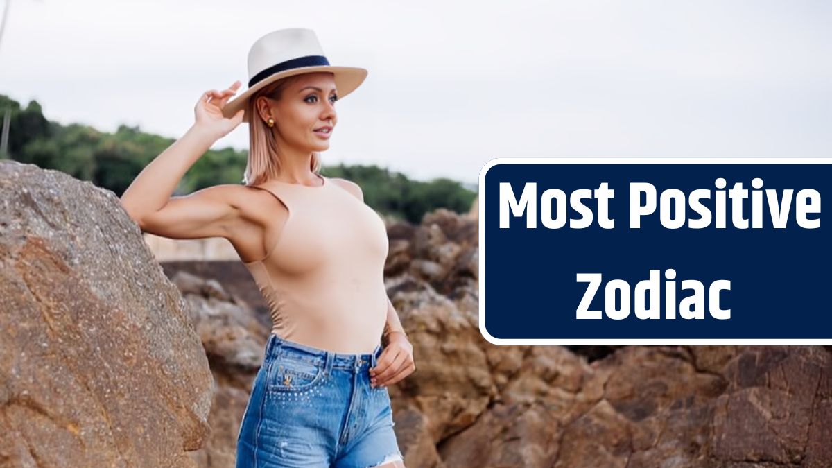 Outdoor fashion portrait of young european woman in beige body bodysuit blue jean shorts and classic stylish hat on tropical rocky beach warm sunset light