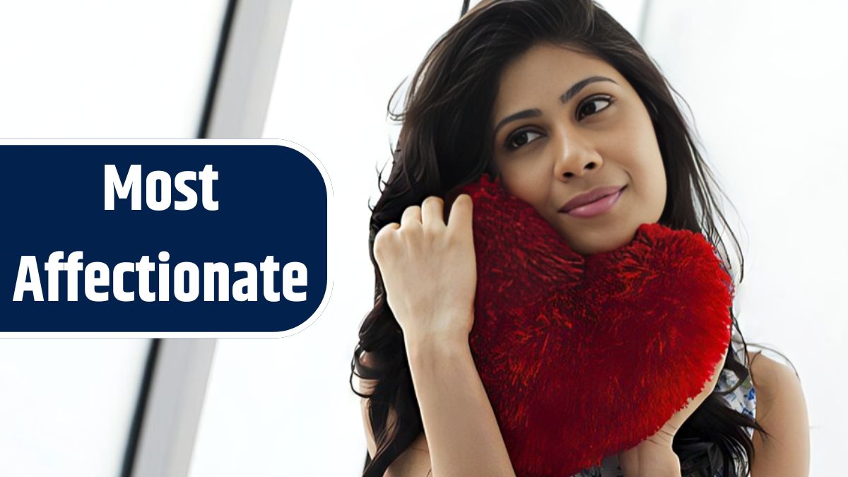 A woman holding a red heart shaped pillow with a smile on her face